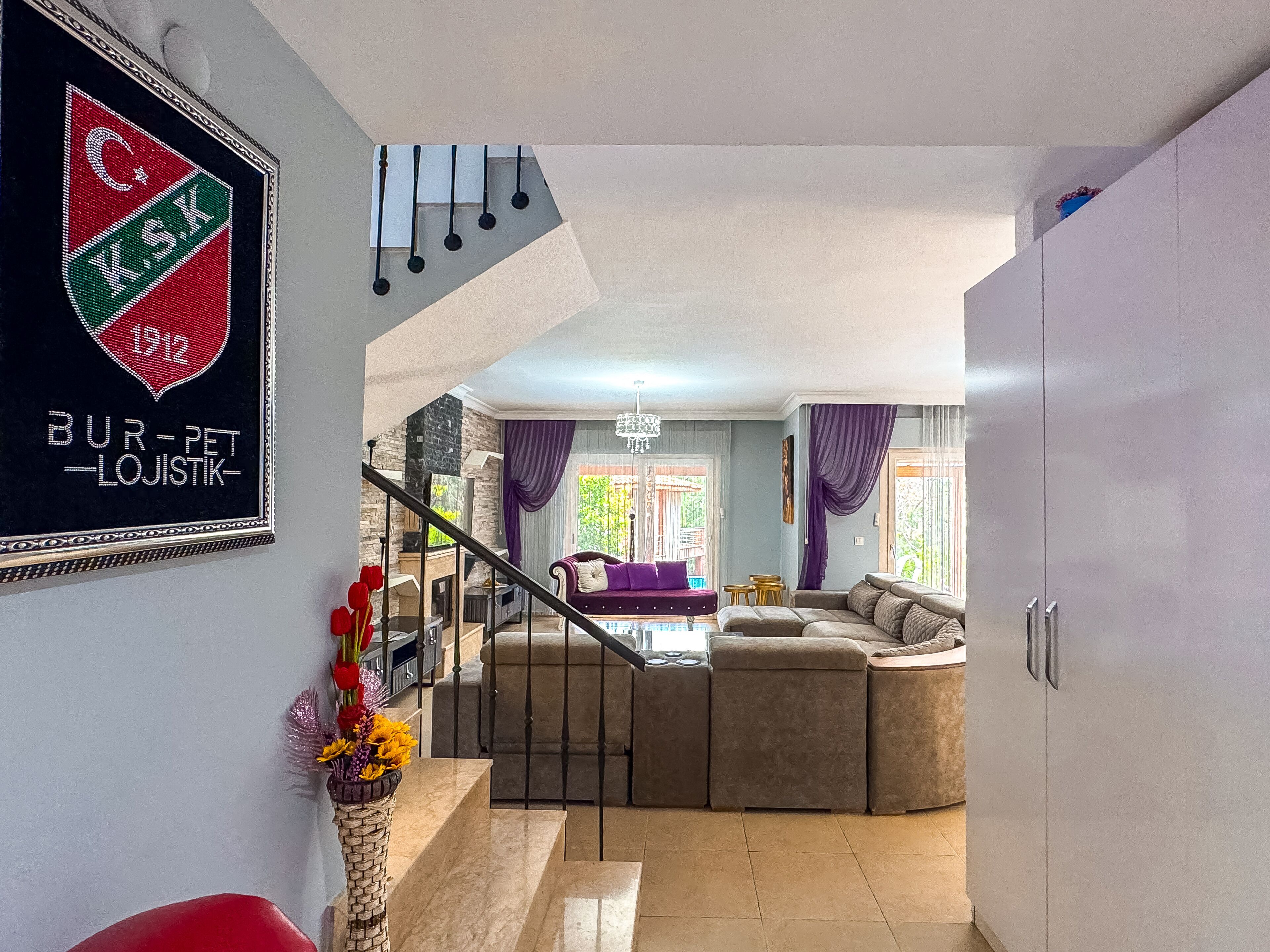 Un'ampia zona giorno con divano, una scala e un elemento decorativo a parete.