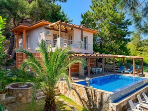 A two-story house with a pool, outdoor seating, and a stone wall. - Villa Siesta (Kusadasi)