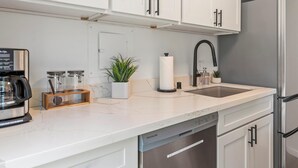 A modern kitchen with white cabinets, a stainless steel refrigerator, a coffee maker, and a sink. - Summer Deal Ground Floor Kihei Condo Walk to Beach and Surf Spots (Kihei)