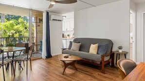 A modern living room with a wooden floor, a grey sofa, a coffee table, and a ceiling fan. - Summer Deal Ground Floor Kihei Condo Walk to Beach and Surf Spots (Kihei)