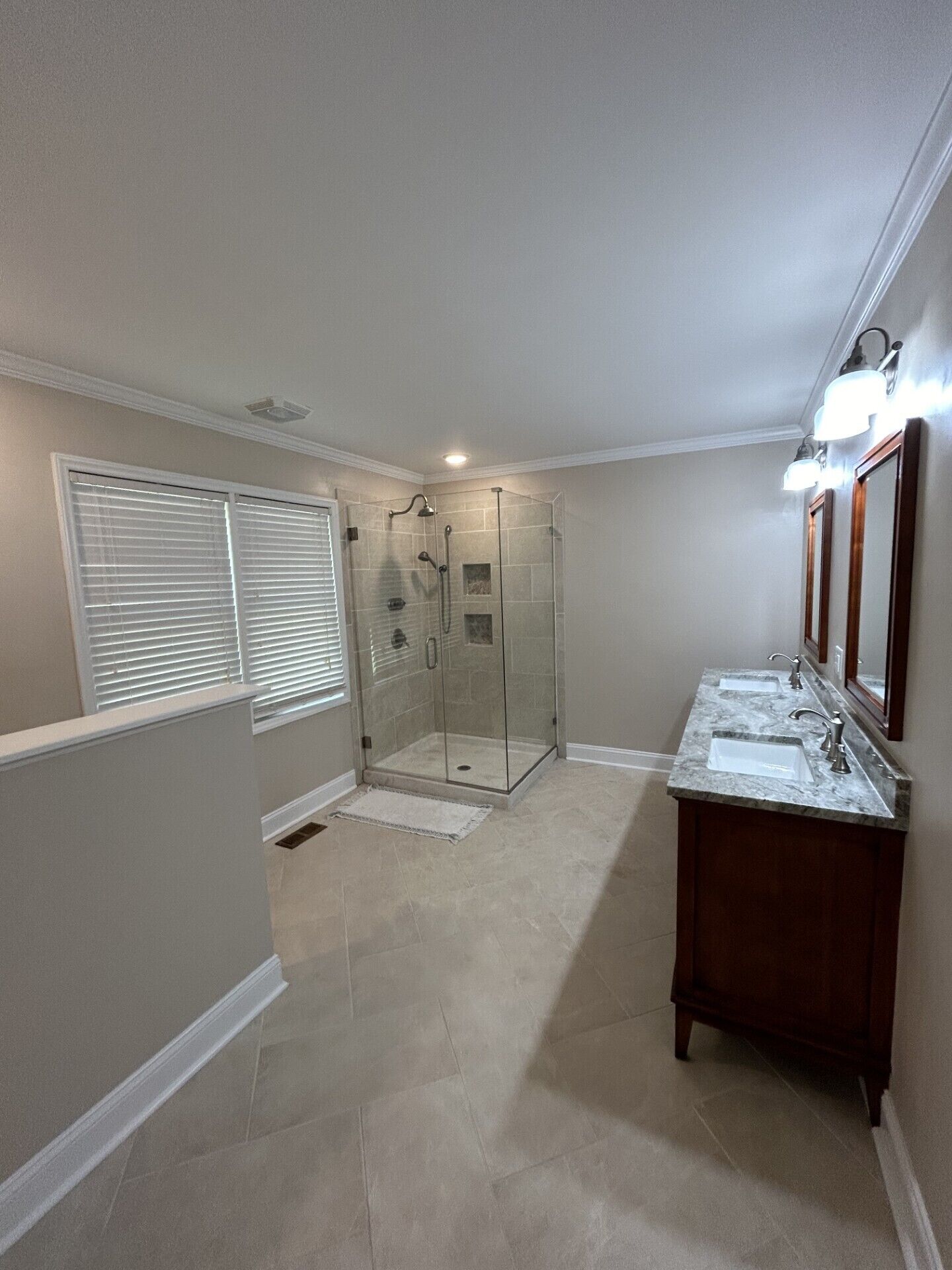 A bathroom with a glass-enclosed shower, two sinks, and a large mirror.