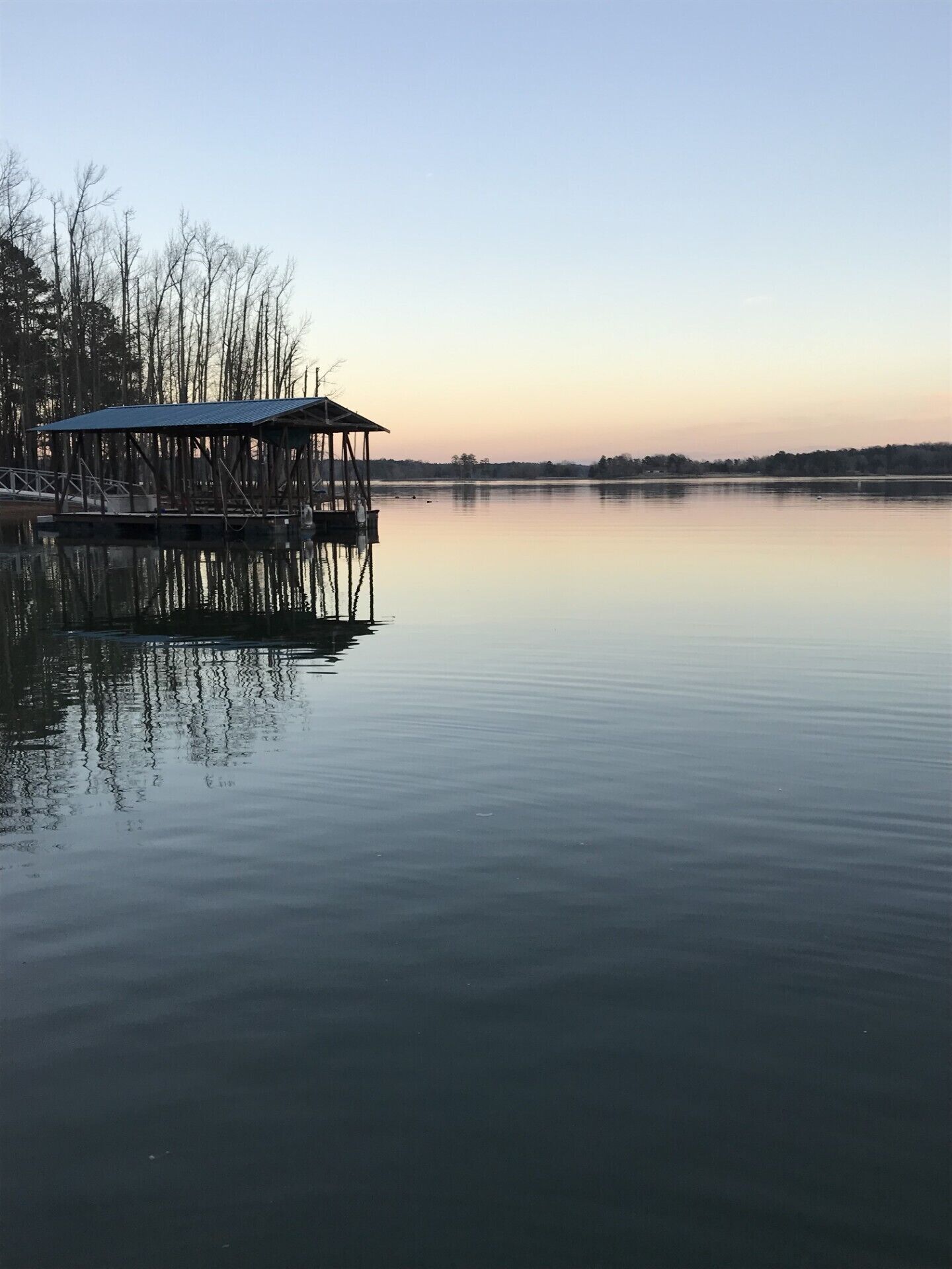 A tranquil lakeside scene with a wooden pier and a covered structure.