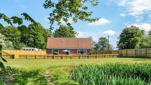 Et hus med røde tegltage, murstensfacade og træhegn.