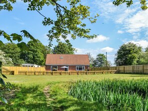 Et hus med røde tegltage, murstensfacade og træhegn.