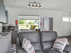 Et moderne køkken med spiseplads, en grå sofa og et køleskab.