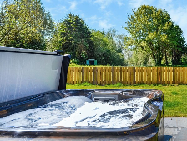 Een hottub met een houten omheining en bomen op de achtergrond.