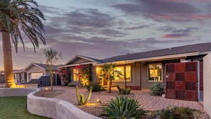 Una casa moderna con un jardín bien cuidado, que incluye cactus y una palmera.