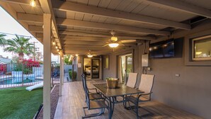 Un patio cubierto con piscina, mobiliario exterior y ventilador de techo.