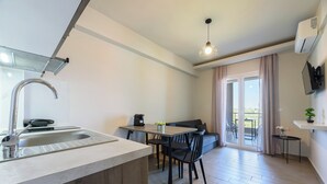 A modern kitchen with a built-in sink and dining area, a ceiling light, and a view of a balcony. - Philippos Residences (Dio-Olympos)