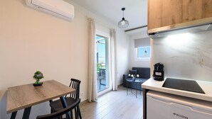 A compact kitchen with a dining area, a built-in oven, and a coffee machine. - Philippos Residences (Dio-Olympos)