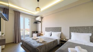 A hotel room with a large bed, a smaller bed, a desk, and a balcony with curtains. - Philippos Residences (Dio-Olympos)