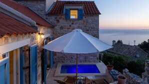 Un bâtiment en pierre doté d’une piscine, d’un espace extérieur aménagé et offrant une vue sur la mer.