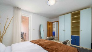 A hotel room with a bed, a wardrobe, a mirror, and a surfboard. - Holiday flat with air conditioning and internet (Umag)