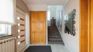 A hallway with a wooden door, a radiator, a black mat, a staircase, and a wall-mounted mirror. - Holiday flat with air conditioning and internet (Umag)
