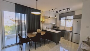 Eine moderne Küche mit Essbereich, großen Fenstern und Blick ins Freie.