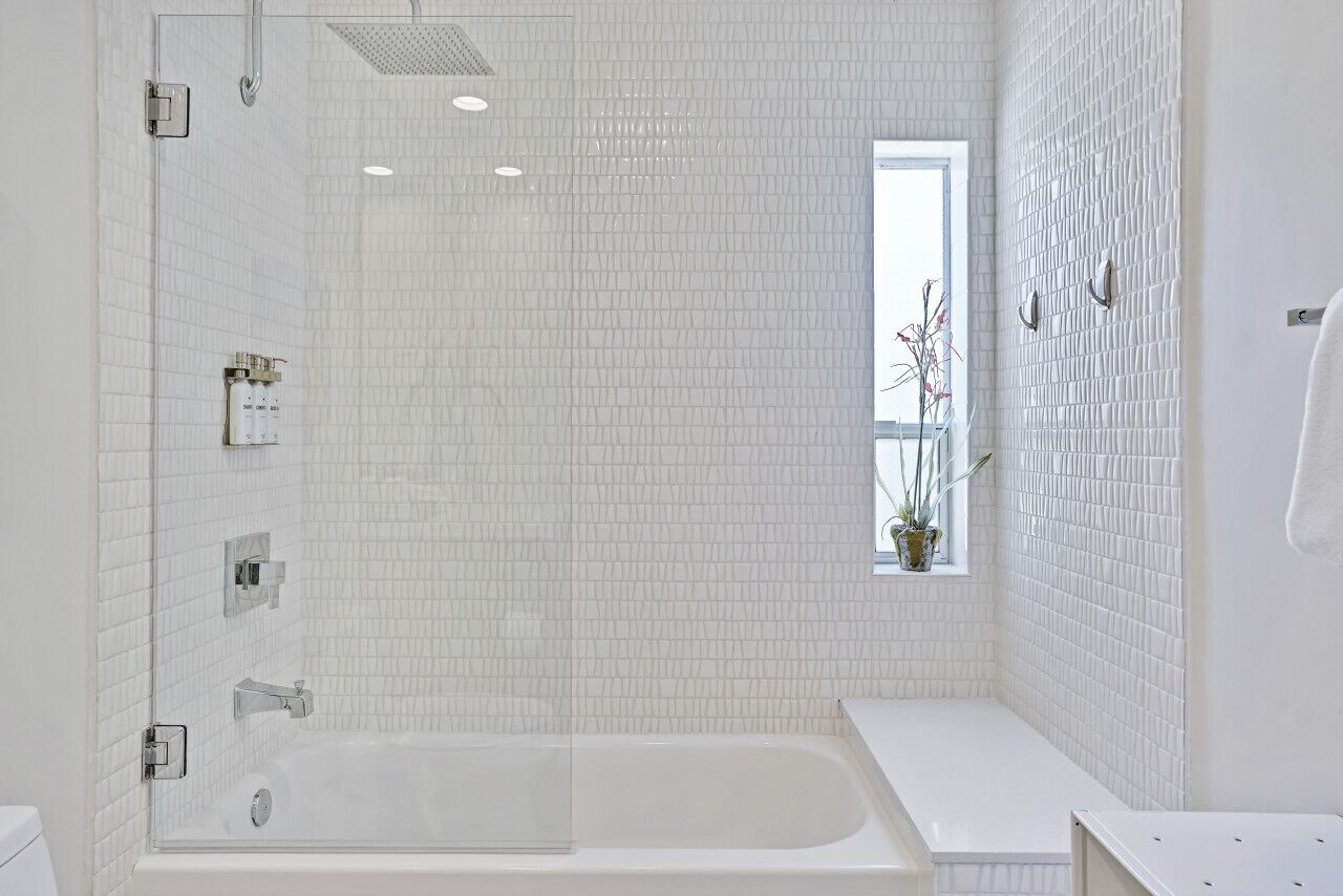 A modern bathroom with a large bathtub, a shower, and a window with a view.