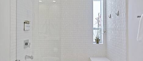 A modern bathroom with a large bathtub, a shower, and a window with a view.