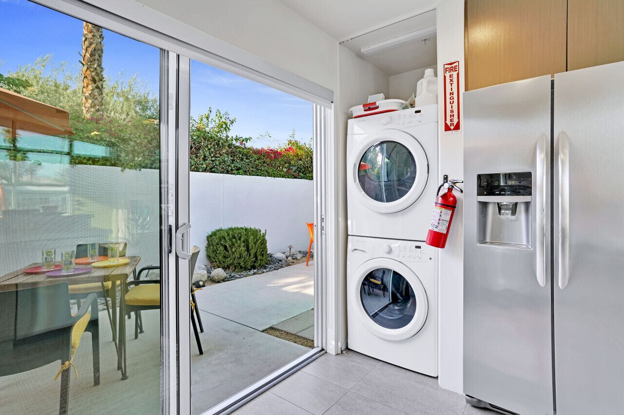 Un espace buanderie compact comprenant un lave-linge, un sèche-linge et un distributeur d’eau.