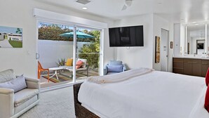 A modern hotel room with a large bed, a flat-screen TV, a balcony with a table and chairs, and a sliding glass door to the outside. - The Vista: Colorful & Vibrant Palm Springs Escape (Palm Springs)
