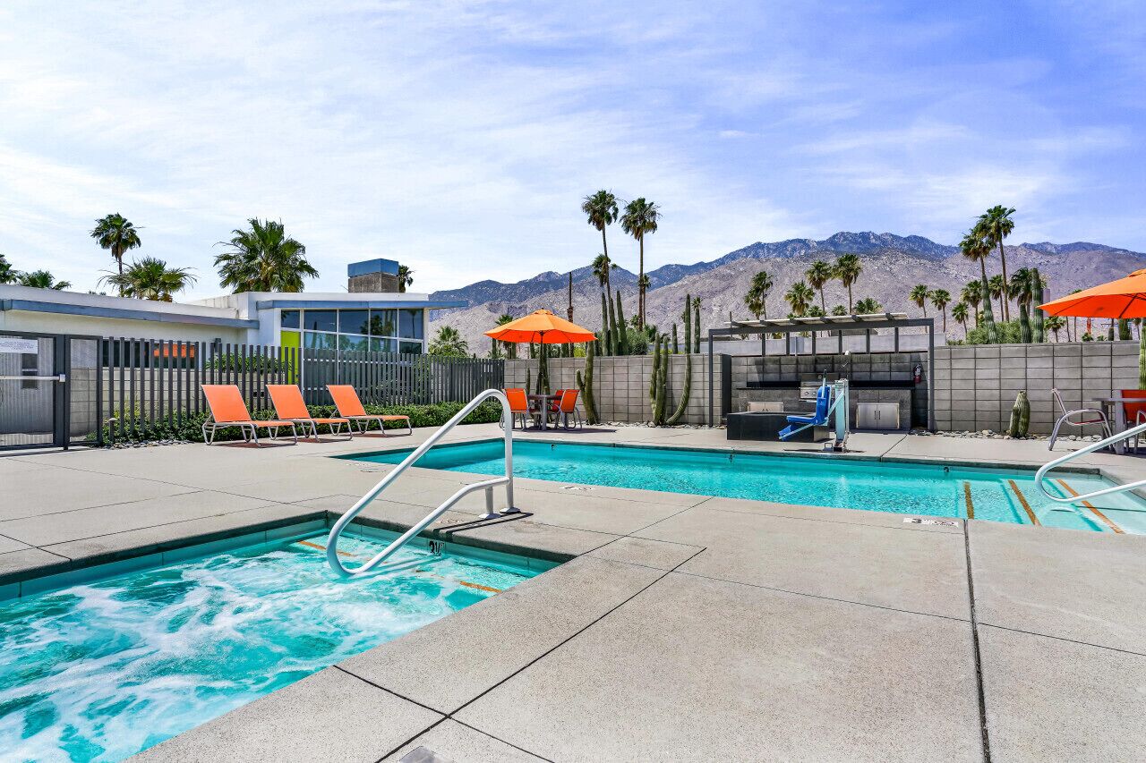 A pool area with lounge chairs, a hot tub, and a mountain view.