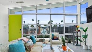 A modern living room with a large window, a green door, and a seating area with a sofa and armchairs. - The Vista: Colorful & Vibrant Palm Springs Escape (Palm Springs)