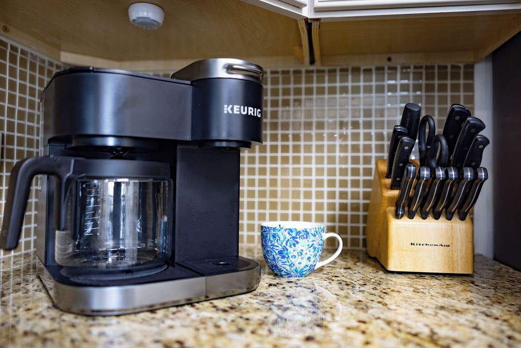 A coffee maker, a cup, and a knife block on a kitchen counter.
