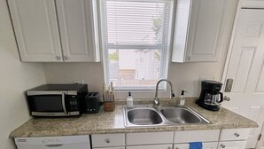 Una cocina compacta con un lavamanos doble, un microondas, un tostador y una cafetera.