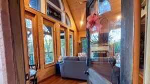 A cozy wooden interior with a dining area, a sofa, and a large window. - The Sunrise Cabin w/ Amazing  Views (Lampe)