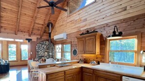 A spacious kitchen with wooden cabinets, a stone fireplace, and a large island. - The Sunrise Cabin w/ Amazing  Views (Lampe)