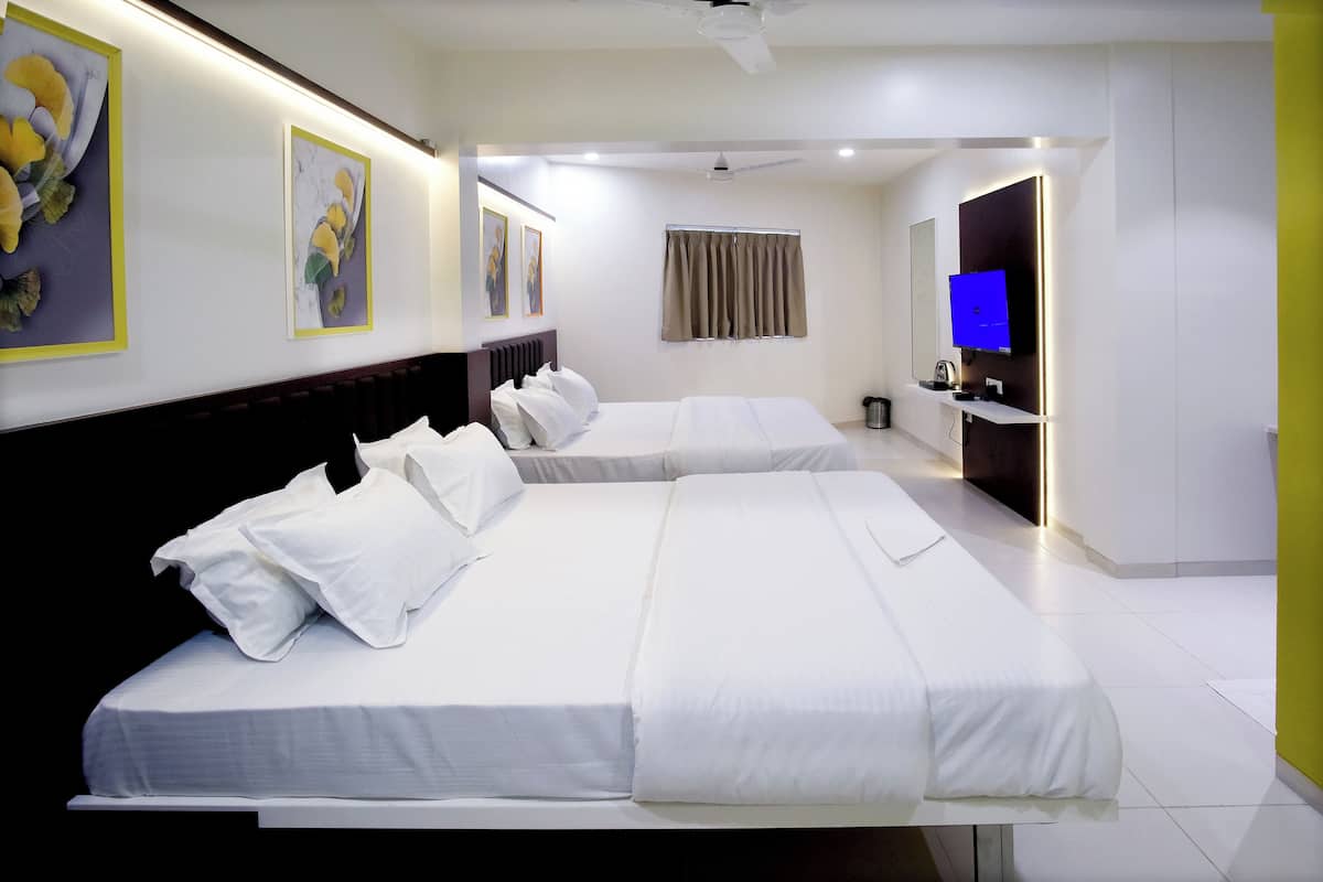 Quarto de hotel moderno com duas camas, televisão de tela plana e obras de arte nas paredes.