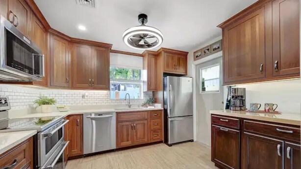 Una cocina moderna con armarios de madera, electrodomésticos de acero inoxidable y una isla central.
