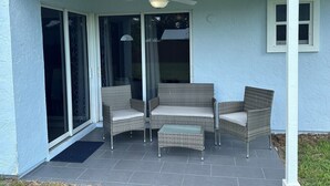 A covered patio with wicker furniture and a ceiling fan. - Home Away From Home! (Vero Beach)
