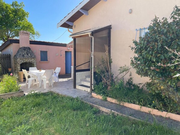 Enjoy a peaceful patio with a fireplace, seating area, and lush greenery.