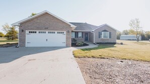 Ein zweigeschossiges Haus mit Garage, einem kleinen Anbau und einem gepflegten Rasen.