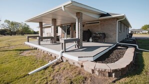 Ein überdachter Patio-Bereich mit Grill und Sitzgelegenheiten.