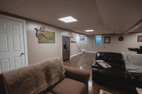 A spacious hallway with a refrigerator, a couch, and a door.