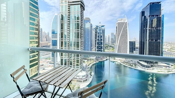 A balcony with a view of modern skyscrapers and a marina.