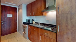 A compact kitchen with wooden cabinets, a stainless steel sink, a microwave, and a built-in oven.