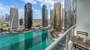 A high-rise building with a curved facade overlooking a body of water and other high-rise buildings.
