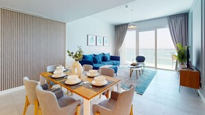 Ein modernes Wohnzimmer mit Essbereich, einem blauen Sofa und Meerblick.