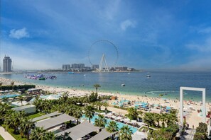 A beach resort with a large pool area, palm trees, and a Ferris wheel in the background. - Breathtaking 2 Bedroom l Ain Dubai &  Sea Views (Jumeirah Beach Residence)