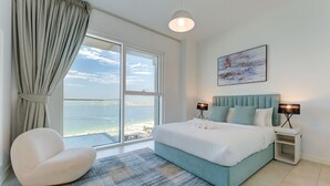 Ein Schlafzimmer mit großem Fenster, einem Bett, einem Sessel und einem Gemälde an der Wand.