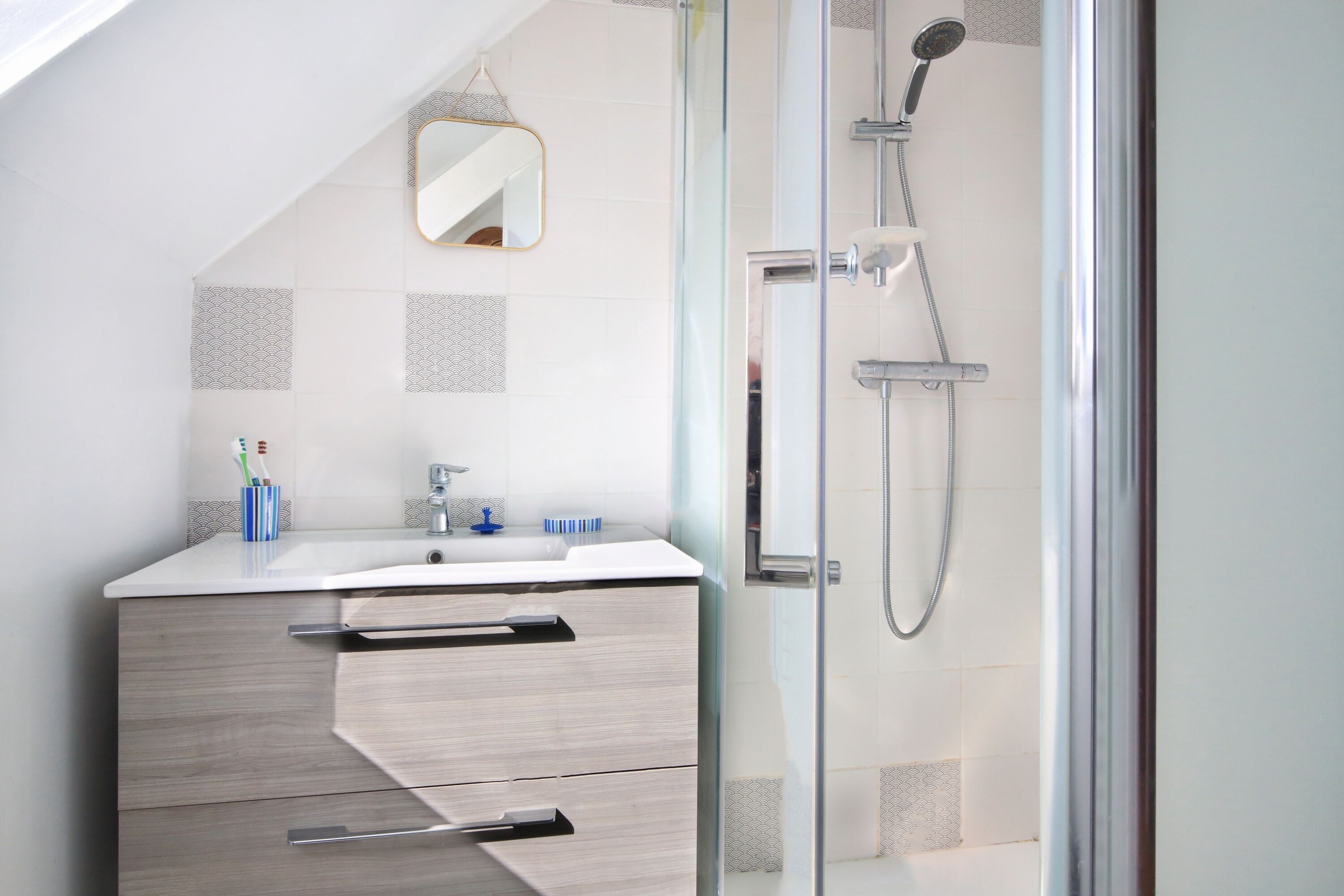 A modern bathroom with a shower, a sink, and a mirror.