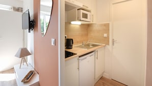 A compact kitchen with a microwave, sink, and a small countertop. - Chez Flora - Appartement pour 4 (Saint-Aubin-sur-Mer)