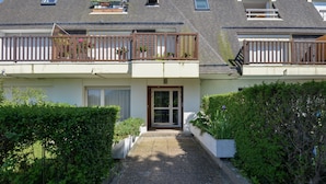 A two-story residential building with a gravel pathway leading to the entrance. - Chez Flora - Appartement pour 4 (Saint-Aubin-sur-Mer)