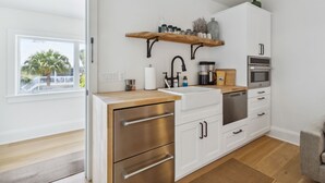 A modern kitchen with white cabinets, stainless steel appliances, and a wooden countertop.