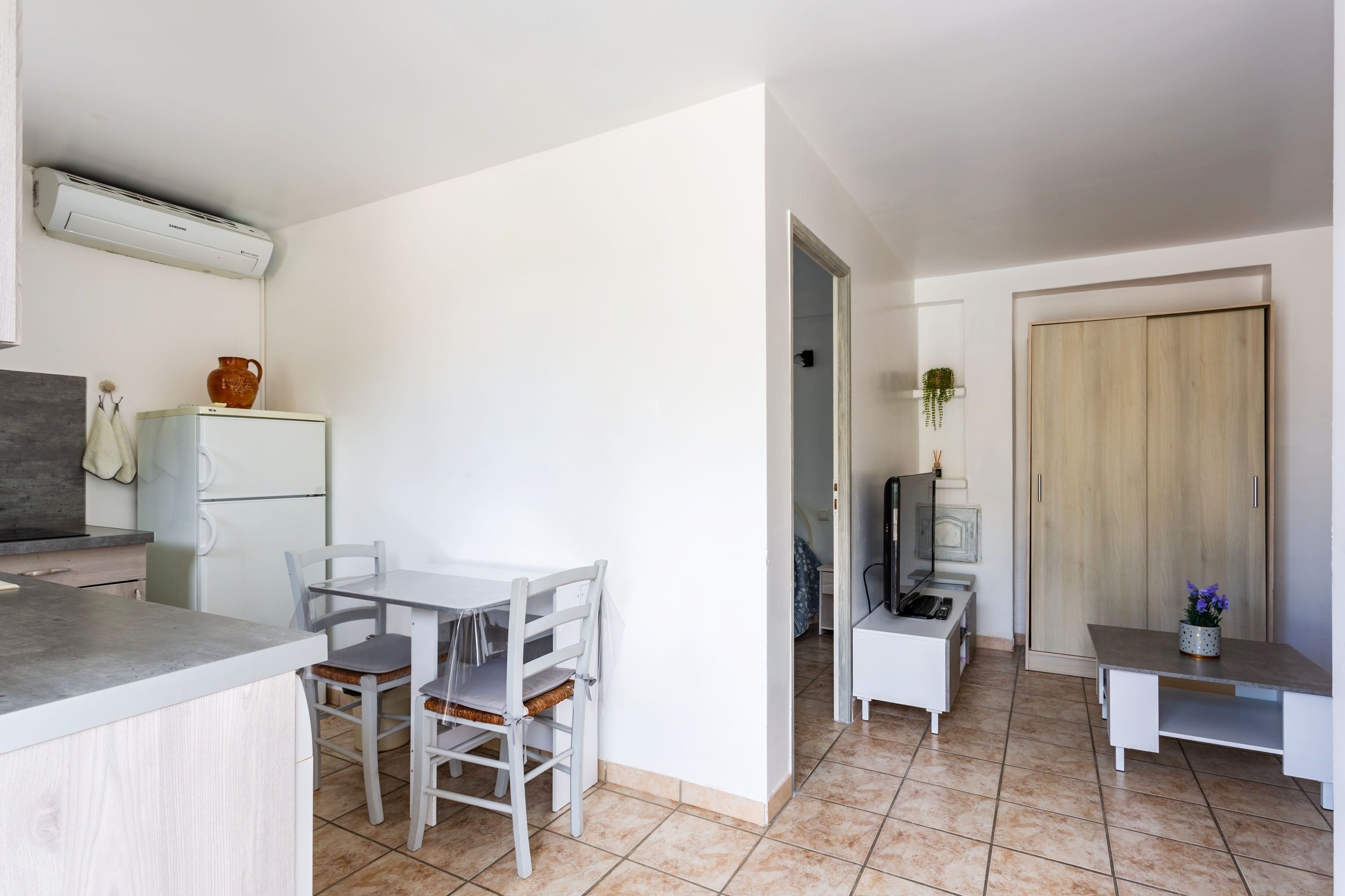 Une cuisine compacte avec un coin repas, une petite télévision et une armoire en bois.