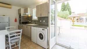 A compact kitchen with a built-in washer, a dining table, and a view of the outdoor area.