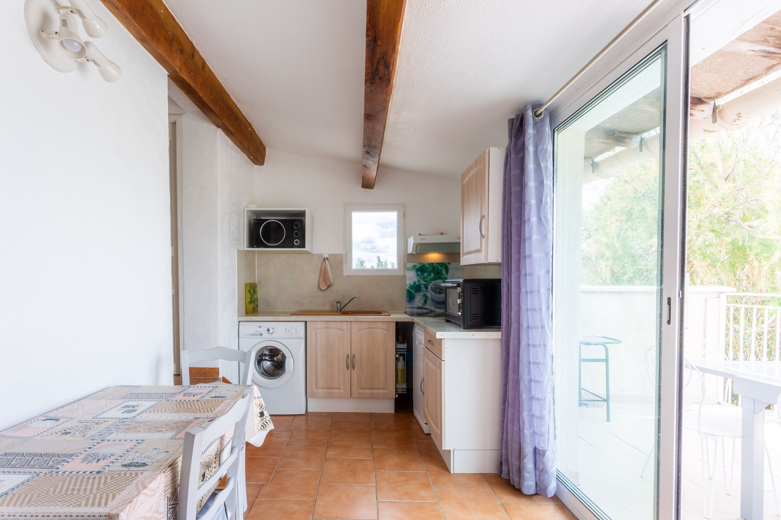 A compact kitchen with a washing machine, a microwave, and a small dining area with a table.