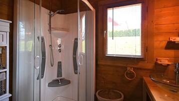 Een moderne badkamer met een douchecabine van glas, houten wanden, een wastafel en een raam met zonwering.